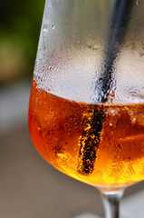 glass of fresh sparkling bubbles in orange aperol spritz drink cocktail with black drinking straw 