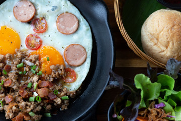 Fried eggs in a frying pan with  Smoked sausage and bread for breakfast on  background.