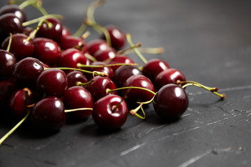 Cherries scattered on a black table. Red ripe berries on black stone table