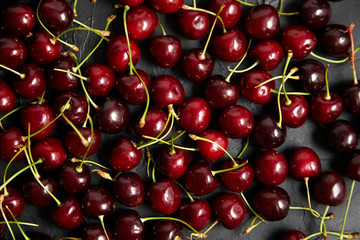 Cherries background. Red ripe berries scattered on a black table