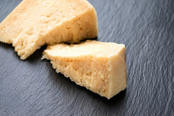 Parmesan cheese on black stone background. Top view, copy space.
