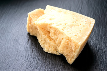Parmesan cheese on black stone background. Top view, copy space.