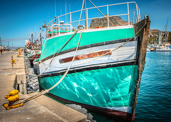 Fototapeta na wymiar Fishing boat docked at Hout Bay Mariners Wharf in Cape Town, South Africa