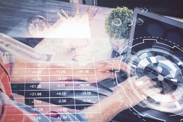 Double exposure of stock graph with businessman typing on computer in office on background. Concept of hard work.