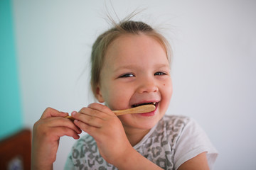child brushes her teeth with bamboo toothbrush