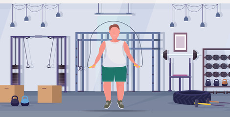fat obese man doing exercises with jumping rope overweight guy training workout weight loss concept modern gym health club studio interior flat full length horizontal