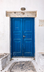 Old blue wooden door of traditional white house in Amorgos, Greece.