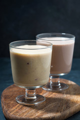 two servings of milkshake in glasses, vertical closeup
