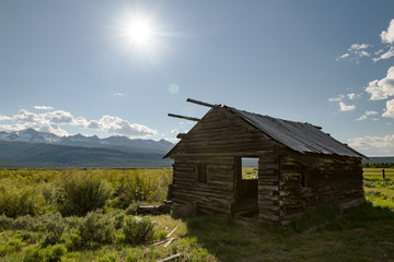 Old log cabin on a meadow near Stanley Idaho with Sawtooth mountains