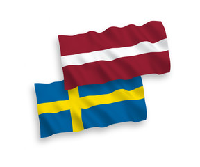 National vector fabric wave flags of Latvia and Sweden isolated on white background. 1 to 2 proportion.