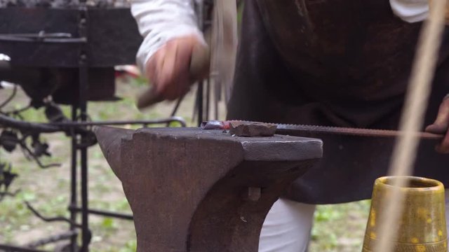 Blacksmith hammering hot piece of metal in outdoor smithy during Slavic and old culture days in Sobotka, Poland.