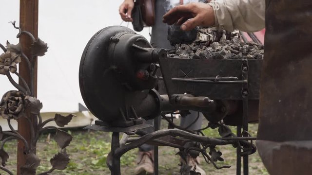 Forge and hand-cranked blower of outdoor smithy, hot rod being moved in coal. Slavic and old culture days in Sobotka, Poland.