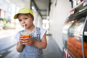 child drinking fresh orange juice through straw