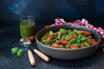 Fusilli pasta with green pesto sauce on a black concrete background. traditional Italian dish.
