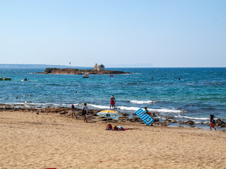 Fototapeta na wymiar People are resting on a sunny day at the beach in Malia, Crete, Greece