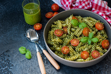 Fusilli pasta with green pesto sauce on a black concrete background. traditional Italian dish.