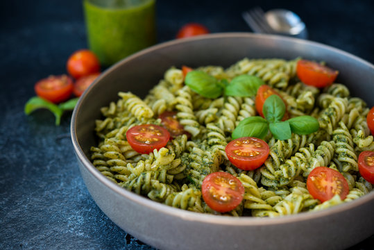 Fusilli pasta with green pesto sauce on a black concrete background. traditional Italian dish.
