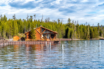 Fototapeta na wymiar Wooden home on Yellowstone Lake with trees water reflections