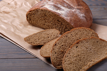 Sliced rustic bread loaf on wooden table. Dark background.