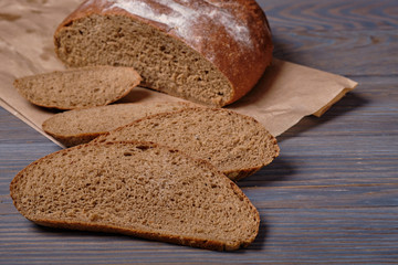 Sliced rustic bread loaf on wooden table. Dark background.