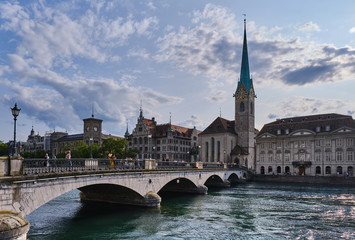 Scenic View Of Bridge Over River Along Buildings Against Blue Sky