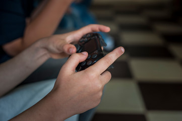 Child holds joystick while sitting on couch at home, playing video game on laptop computer