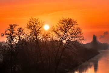 Sunrise over a channel in Berlin on a misty morning with fairytale sunlight.