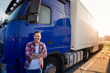 Portrait of middle aged caucasian trucker in casual clothes standing in front of truck long vehicle...