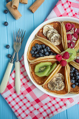 Classic American pancakes with fresh berry on a blue wooden background. Pancakes with fruit. Summer homemade breakfast.