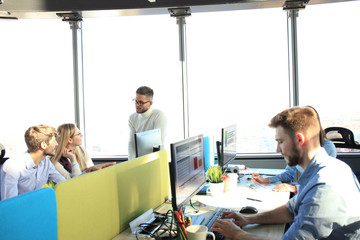 Young modern colleagues in smart casual wear working together while spending time in the creative office.