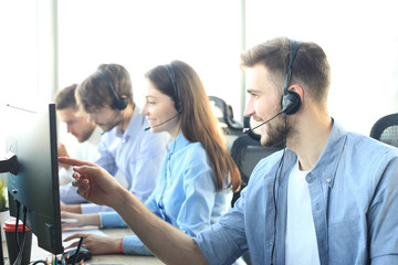 Portrait of call center worker accompanied by his team. Smiling customer support operator at work.