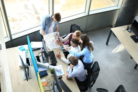 Top view of young modern colleagues in smart casual wear working together while spending time in the office.