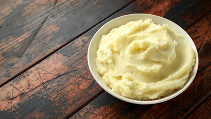 Mashed potatoes in white bowl on wooden rustic table. Healthy food
