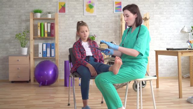 Physiotherapist tells a teenage girl with orthopedic problems about orthopedic insoles for flatfoot correction