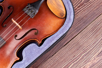 Old violin on wooden background. Purple velvet case with retro violin and copy space. Vintage musical object.