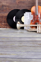 Vintage musical instruments on wooden background. Violin, trumpet, vinyl records and musical notes...