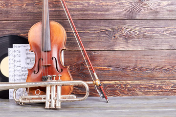 Instruments of orchestra on wooden background. Old violin, trumpet, vinyl records, musical notes...