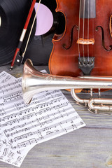Naklejka premium Vintage violin, trumpet and musical notes. Composition from musical instruments on wooden background. Music still life.