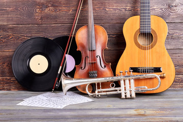 Musical instruments on wooden planks. Trumpet, guitar, violin, plastic disks and musical notes on...