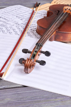 Violin and musical notes on wooden background. Musical background with old viola and music notes, vertical image.