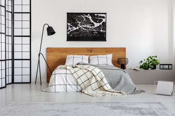 Black map on white wall above wooden headboard in simple bedroom interior