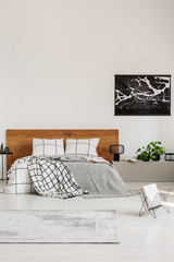 Copy space on white wall with black map in modern bedroom with king size bed with wooden headboard