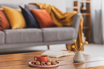 Closeup of elegant wooden coffee table in trendy living room interior with grey sofa with pillows