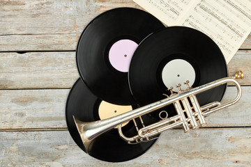 Old trumpet and vinyl records on wooden background. Rusty trumpet, vinyl discs and musical sheets. © DenisProduction.com