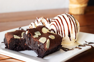 Closeup homemade brownie served with vanila icecream and whipping cream. Sweet dessert for chocolate flavor.