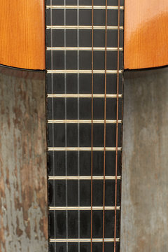 Acoustic guitar fretboard. Guitar on wooden background with fretboard and strings close up, vertical image.