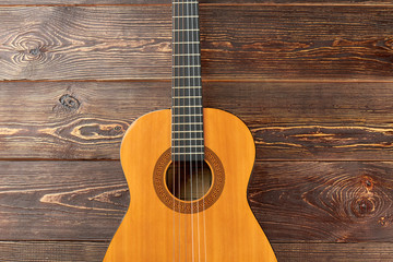 Obraz premium Acoustic guitar on dark wooden background. Ukulele on brown wooden surface. How to play country guitar.
