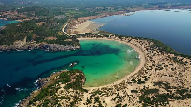 Aerial drone video of semicircular sandy beach and lagoon of Voidokilia, one of the most iconic beaches in Mediterranean sea, with crystal clear turquoise sea, Messinia, Greece