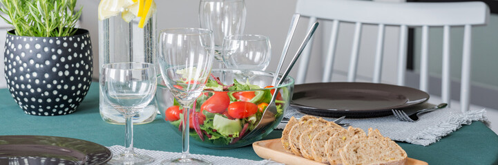 Close-up of wine glasses, salad and bread on a table in a dining room interior