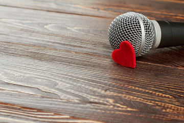 Gray microphone on dark wooden background. Microphone with red heart and copy space. Valentines Day...